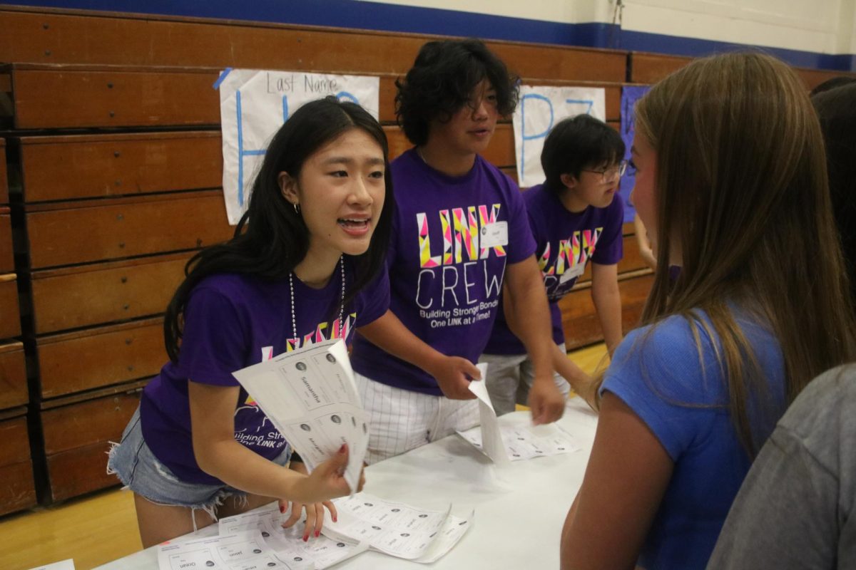 Link Crew leaders Chloe Wang, 11, Justin Lin, 11, and Geoffrey Foong, 11, help freshmen get their name tags.